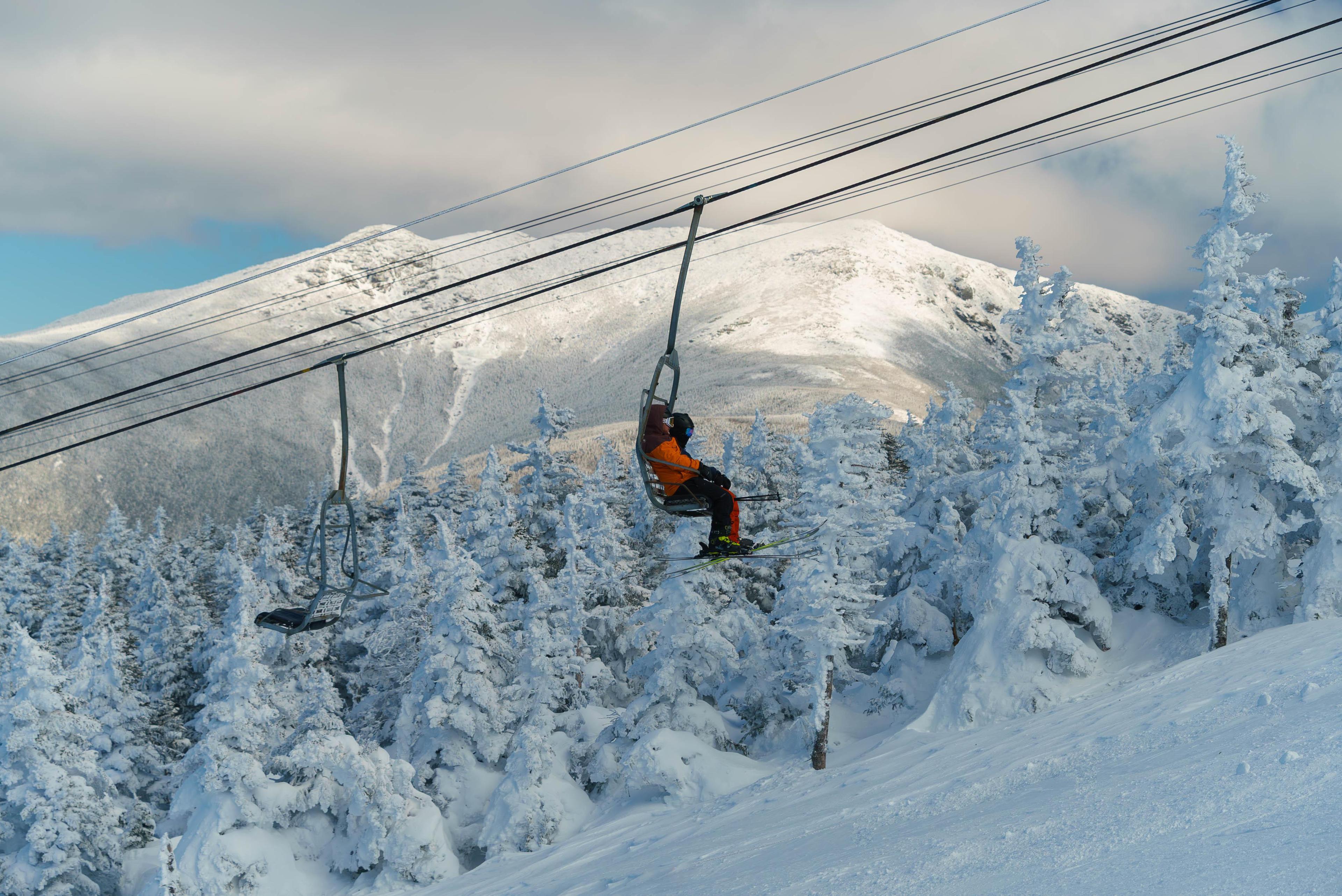 Skiers on Cannonball chair with Franconia ridge in the background