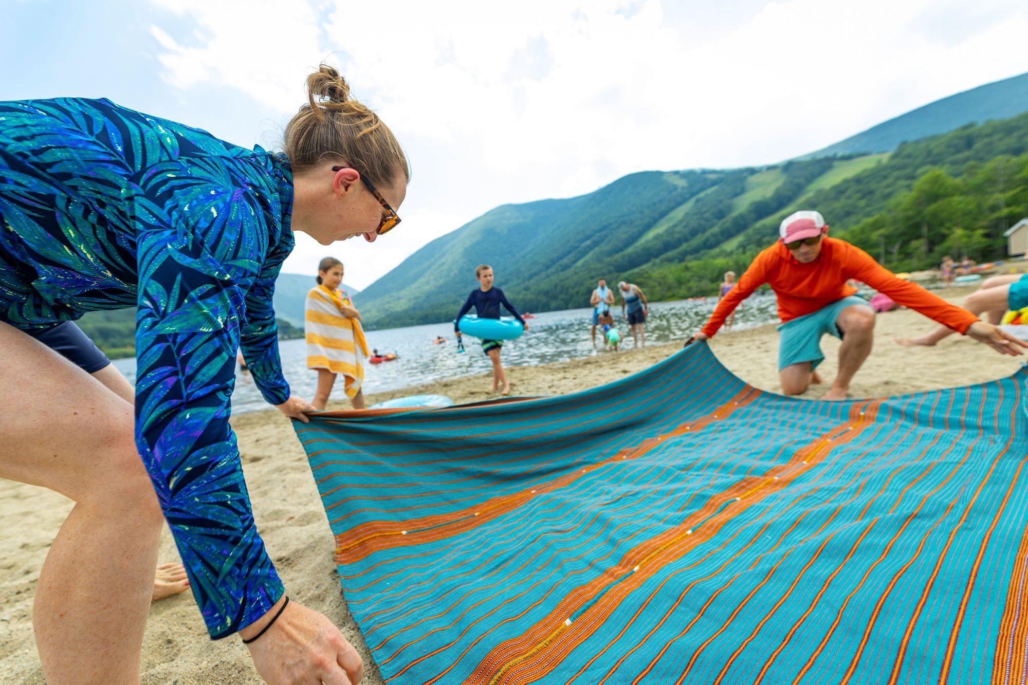 Couple lays down a blanket at the beach