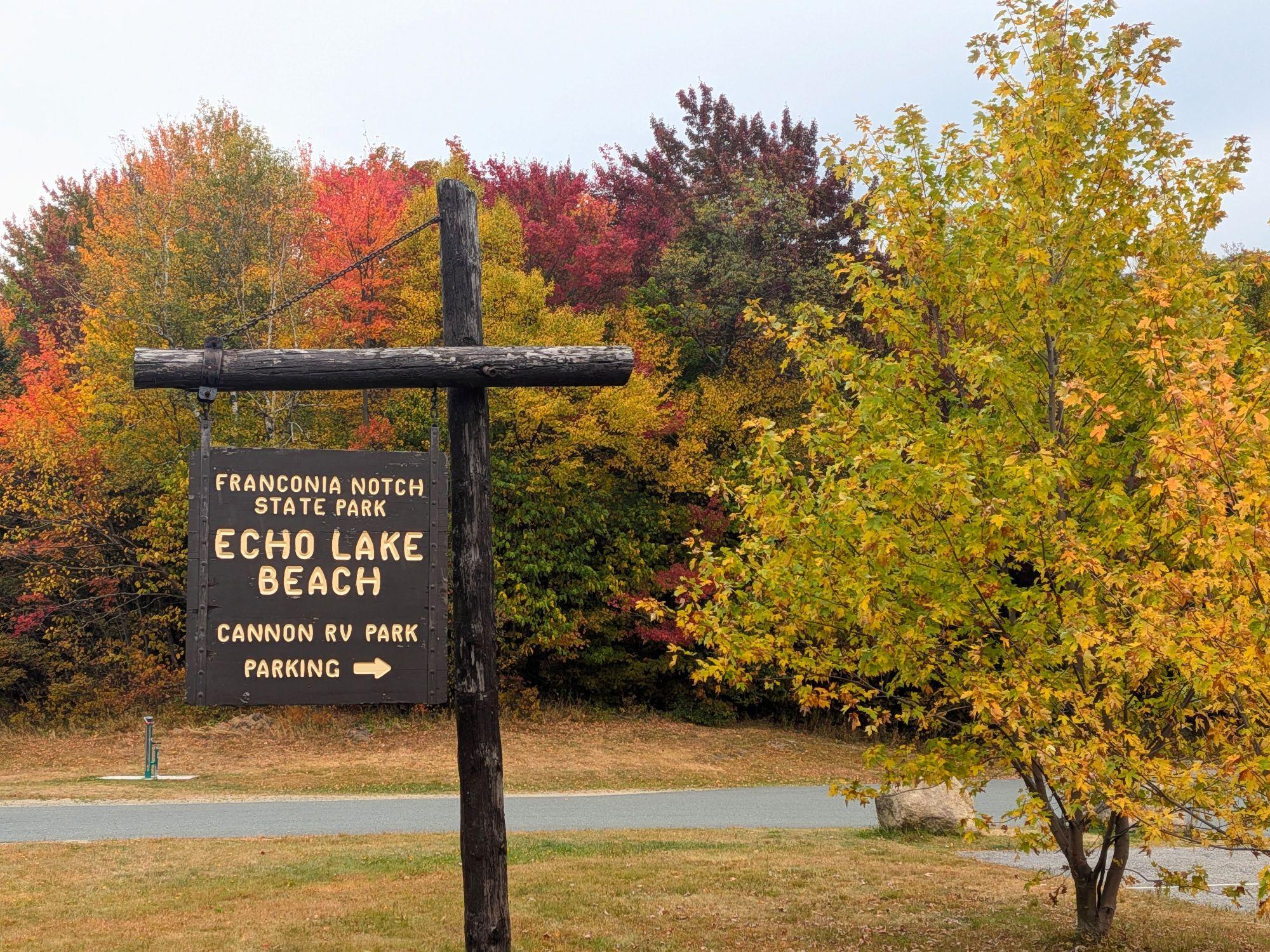 Wooden Echo Lake sign with fall foliage in the background.