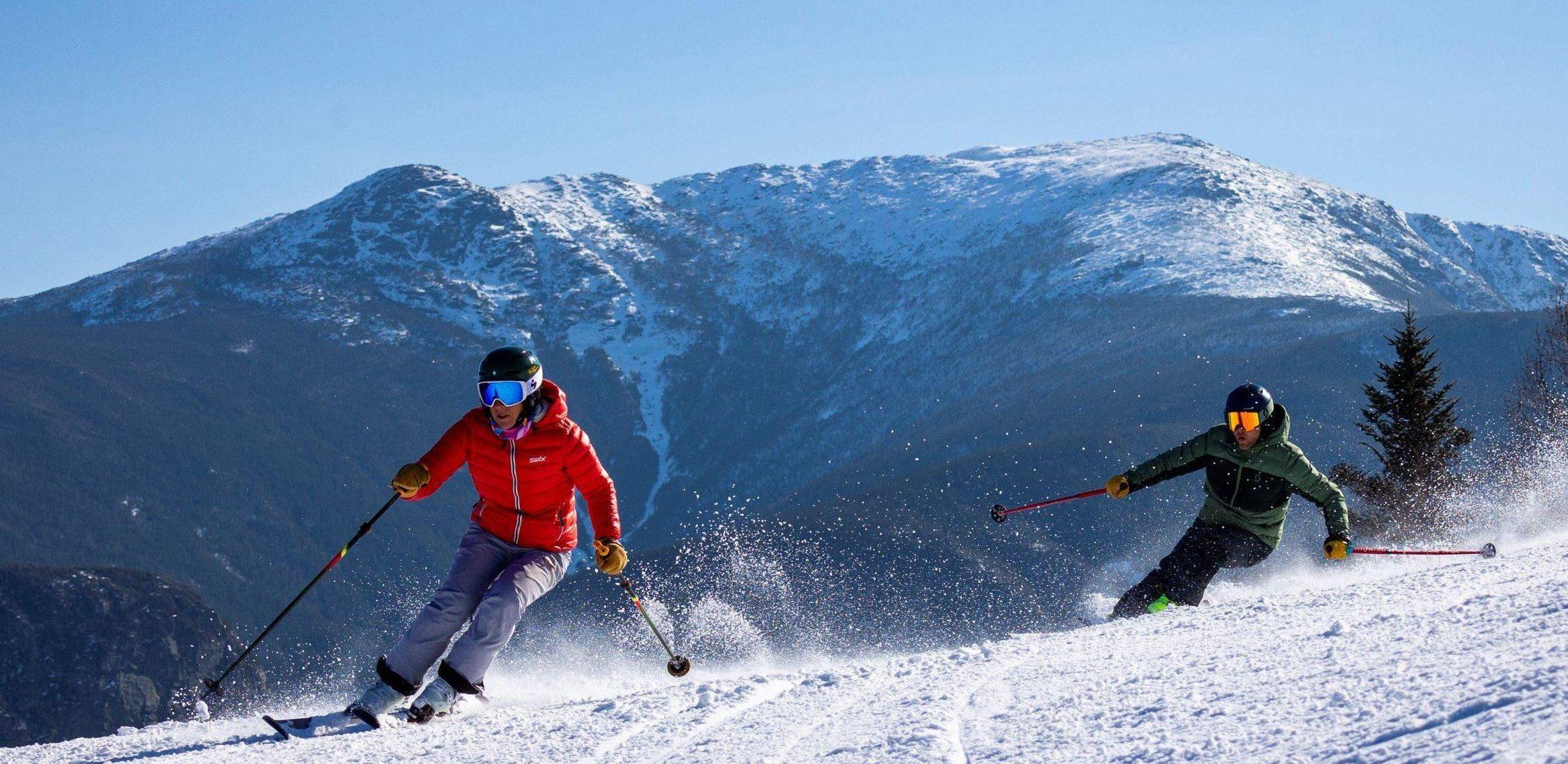 2 skiers carve through rock garden w/ the ridge in the background